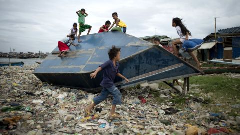 Children play on an overturned boat at the port area of Manila on Sunday, December 7.