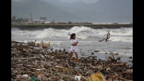 A girl walks along the shore as strong waves hit Atimonan, Philippines, on Saturday, December 6.