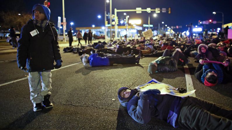 Seven-year-old Elijah Owens, left, stands by people participating in a "die-in" demonstration outside the Philadelphia Eagles' stadium in Philadelphia on Sunday, December 7.