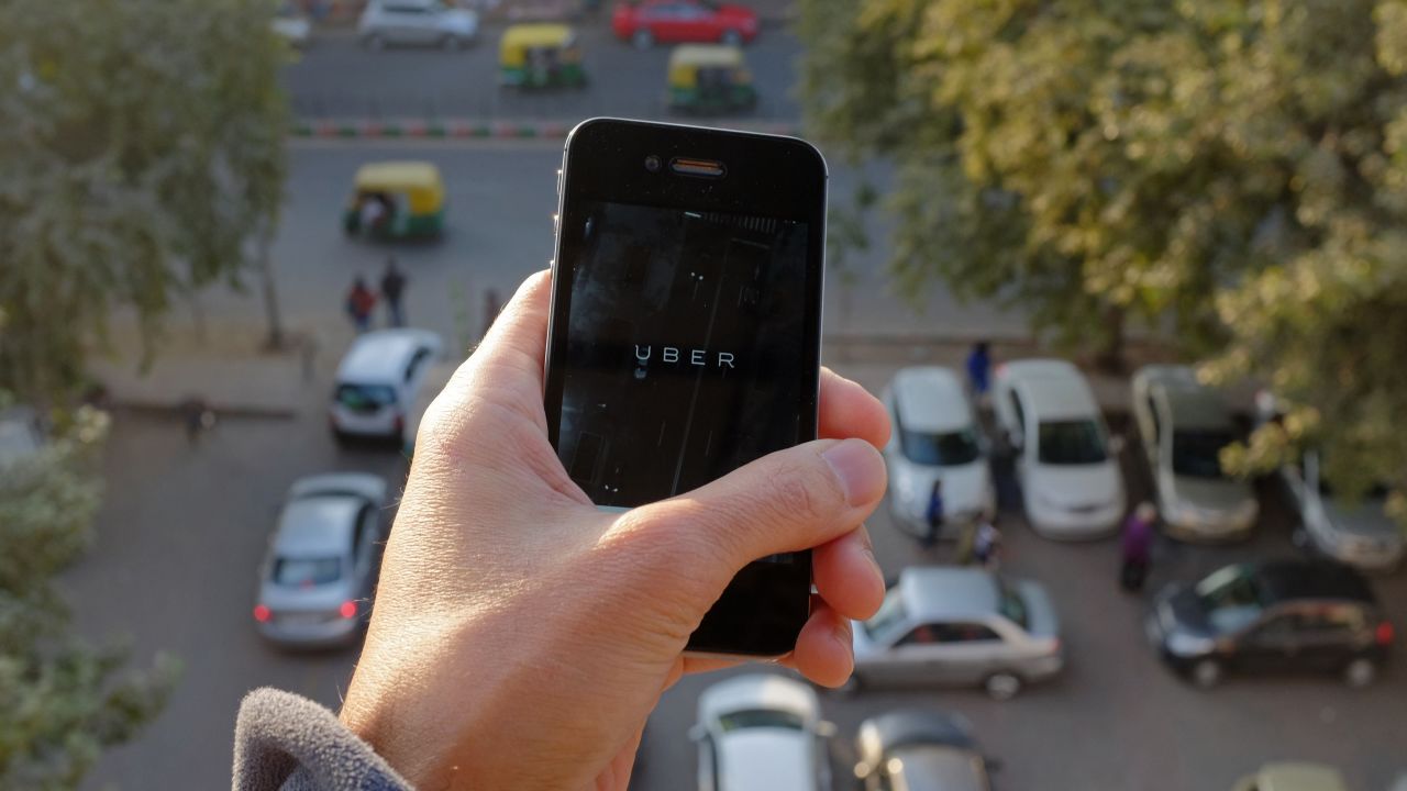 The Uber smartphone app, used to book taxis using its service, is pictured over a parking lot as auto-rickshaws (background) ply a road in the Indian capital New Delhi on December 7, 2014. An Uber taxi driver allegedly raped a 25-year-old passenger in the Indian capital before threatening to kill her, police said December 7, in a blow to the company's safety-conscious image. AFP PHOTO/TENGKU BAHARTENGKU BAHAR/AFP/Getty Images