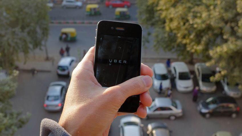 The Uber smartphone app, used to book taxis using its service, is pictured over a parking lot as auto-rickshaws (background) ply a road in the Indian capital New Delhi on December 7, 2014. An Uber taxi driver allegedly raped a 25-year-old passenger in the Indian capital before threatening to kill her, police said December 7, in a blow to the company's safety-conscious image. AFP PHOTO/TENGKU BAHARTENGKU BAHAR/AFP/Getty Images