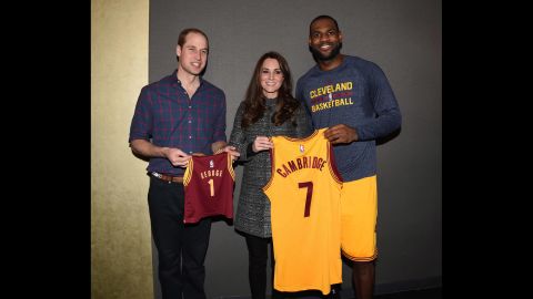 The royal couple poses with basketball star LeBron James after the game. Prince William is holding a jersey made for their son, Prince George.