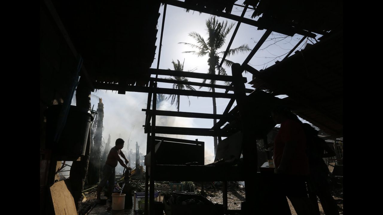 A man collects water near a damaged home in Dolores, Philippines, on Monday, December 8.