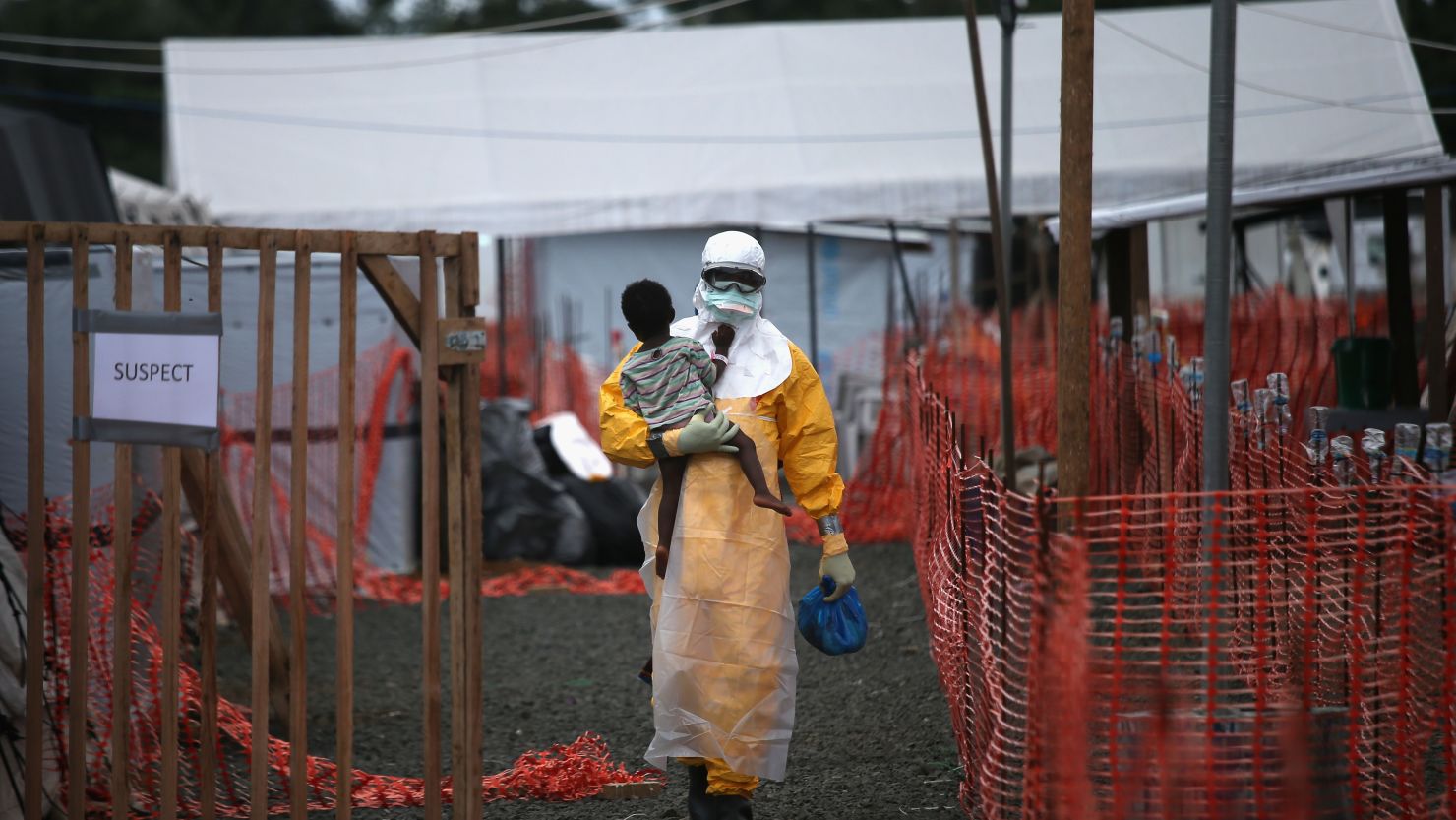 A Doctors Without Borders health worker in protective clothing carries a child suspected of having Ebola in a treatment center in Liberia in October 2014.