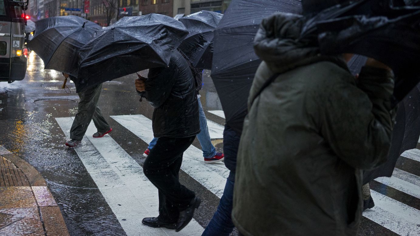 People carrying umbrellas cross a street in New York City on Tuesday, December 9. 