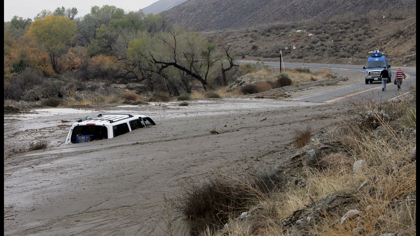 A television news crew walks away from a vehicle caught in an overnight mudslide in San Jacinto, California, on December 4.