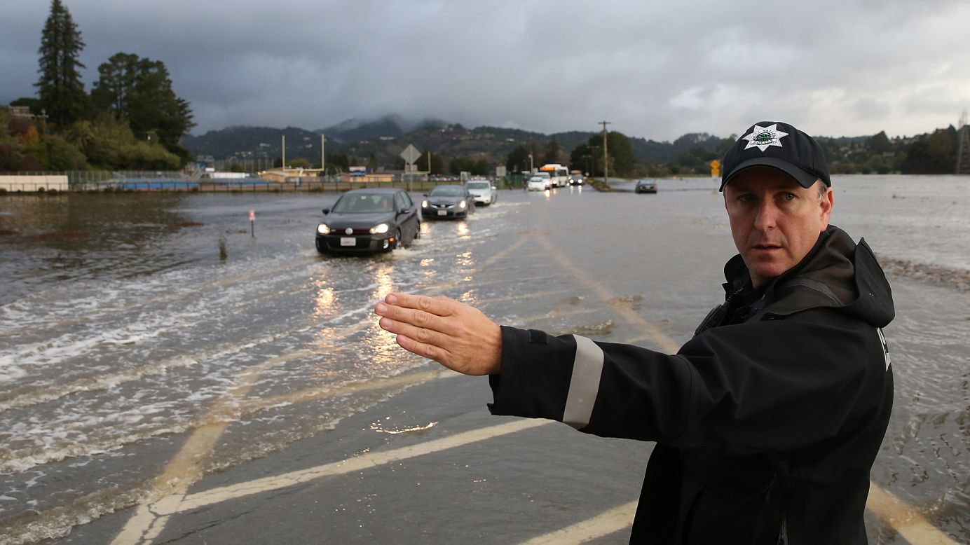 A police officer directs cars through a flooded section of a roadway December 3 in Mill Valley, California.