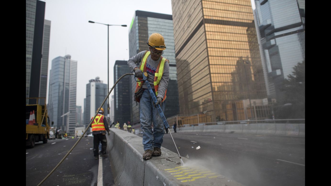 A worker cleans the street after Hong Kong police dismantled the main protest camp December 11.