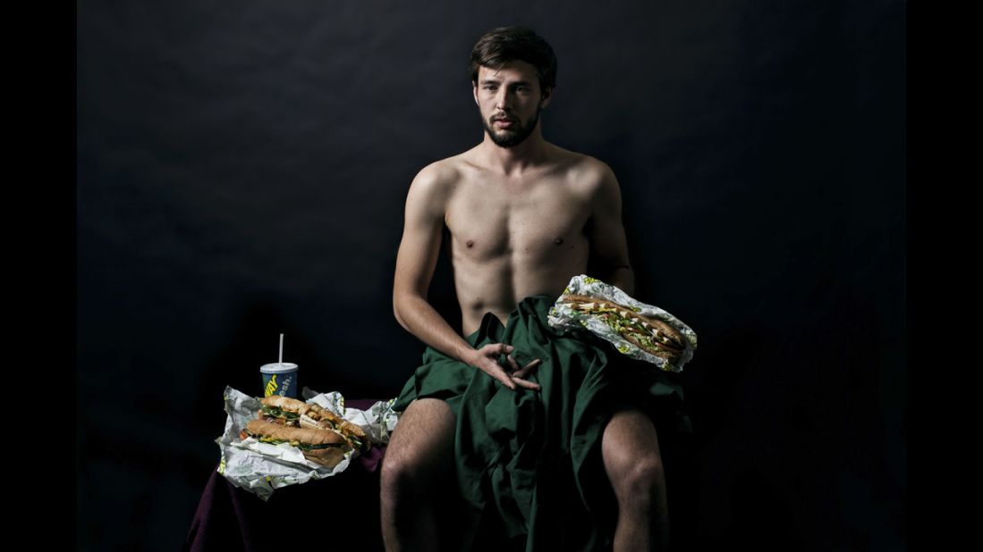 A man poses with Subway sandwiches.