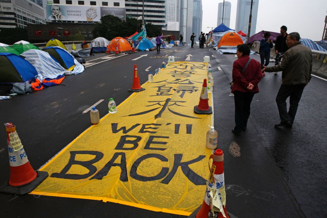 Pedestrians walk past a banner following the end of 2014 pro-democracy protests.