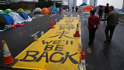 Pedestrians walk past a banner following the end of 2014 pro-democracy protests.
