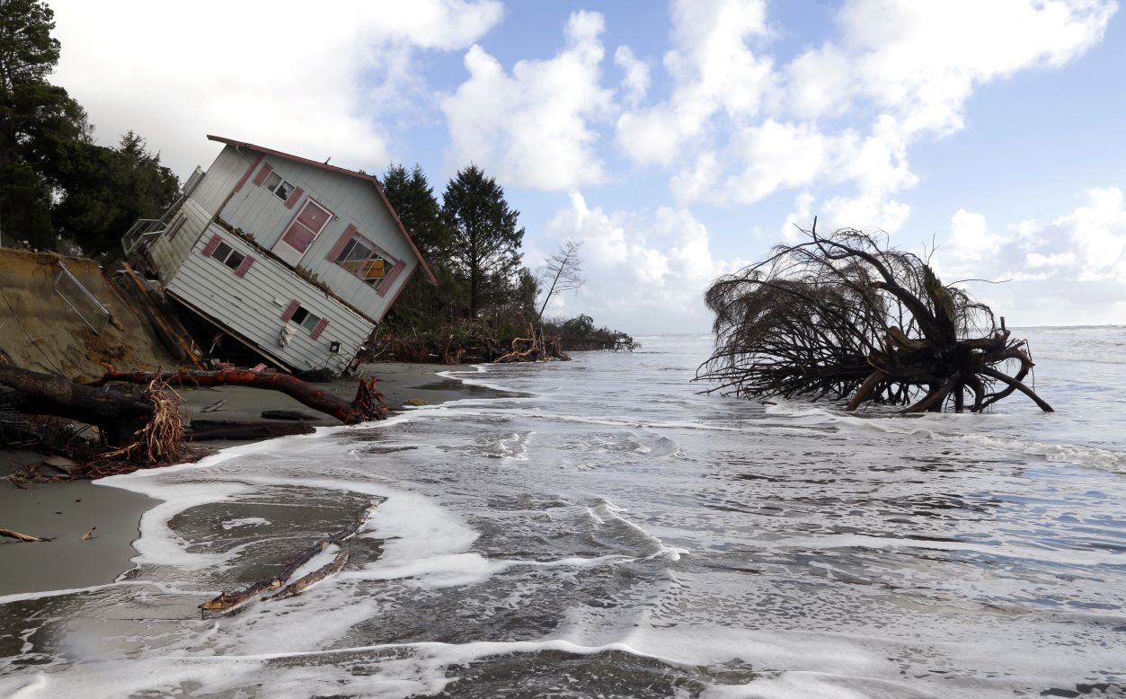A two-story house leaning over the eroding ocean shoreline of North Cove, Washington, is seen on Friday, December 12, as the tide rises. 