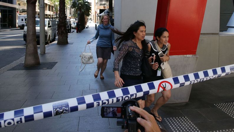 People rush past armed police near the cafe on December 15.