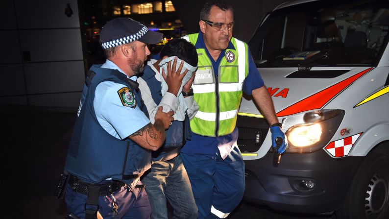 A police officer and a paramedic escort a hostage away from the scene of the siege on December 16.