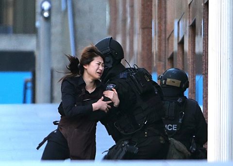 A hostage runs toward police on December 15. She was one of five people seen fleeing the cafe.