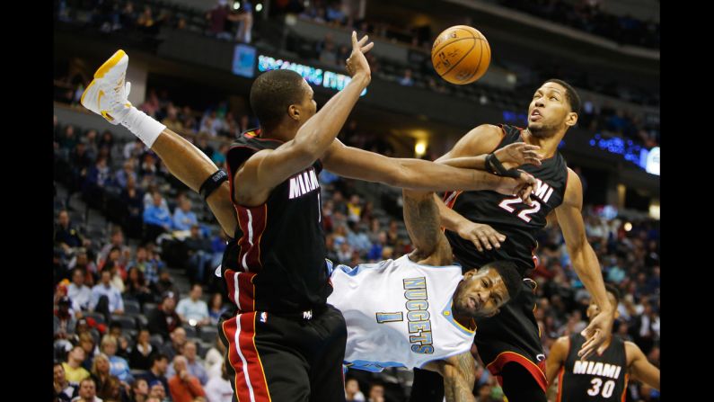 Denver Nuggets forward Alonzo Gee goes horizontal after his shot was blocked by Miami Heat players Chris Bosh, left, and Danny Granger on Wednesday, December 10.