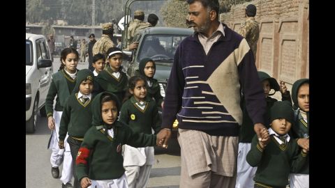 A plainclothes officer escorts rescued students away from the school.