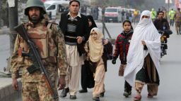 Parents escort their children away from a school in Peshawar, Pakistan, on Tuesday, December 16.