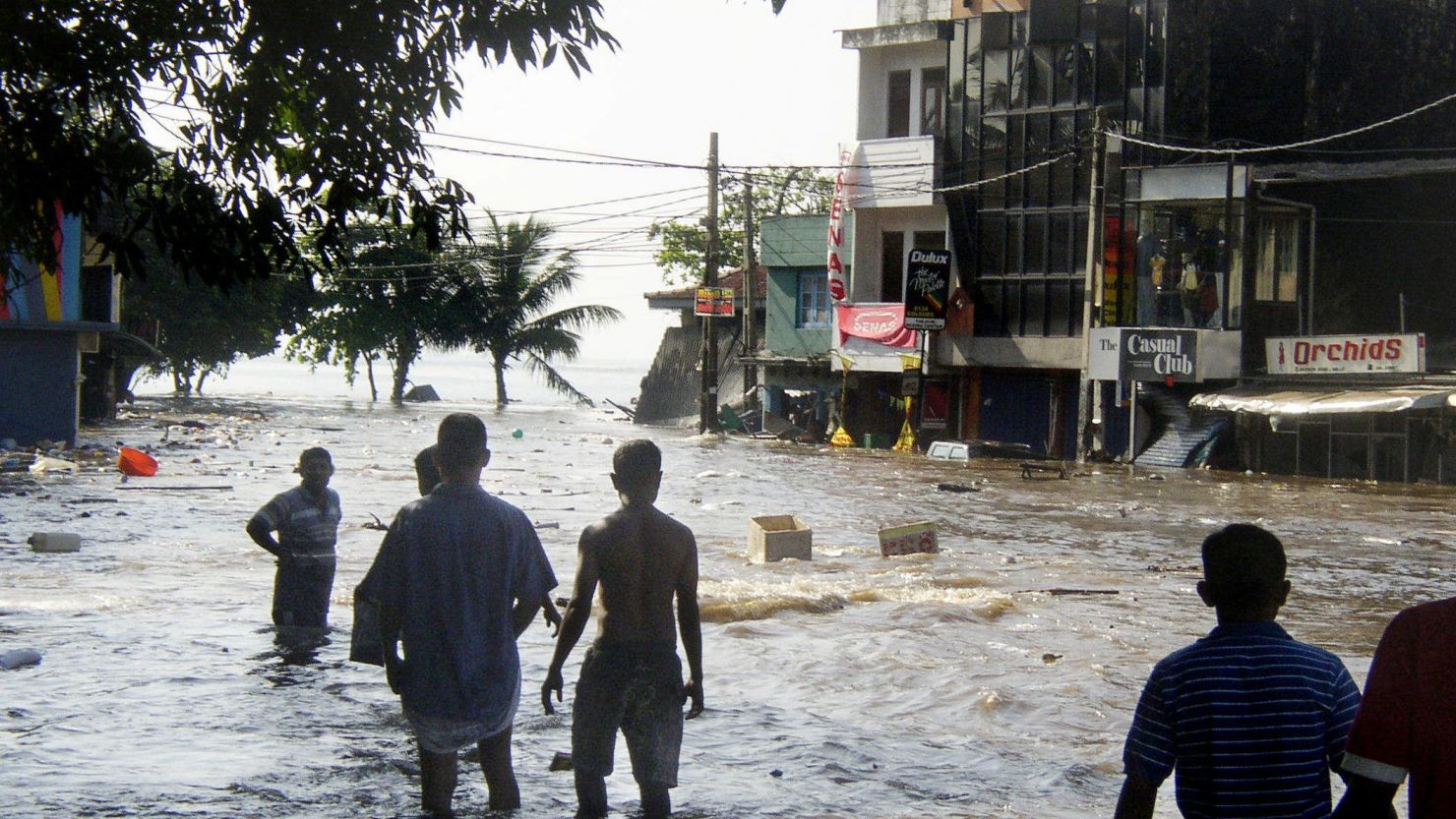 In this picture taken 26 December 2004, Sri Lankan pedestrians walk through floodwaters in a main street of Galle, after the coastal town was hit by a tidal wave.