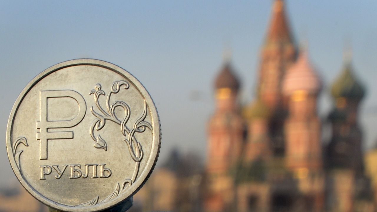 A Russian ruble coin is pictured in front of St. Basil cathedral in central Moscow, on November 20, 2014. 