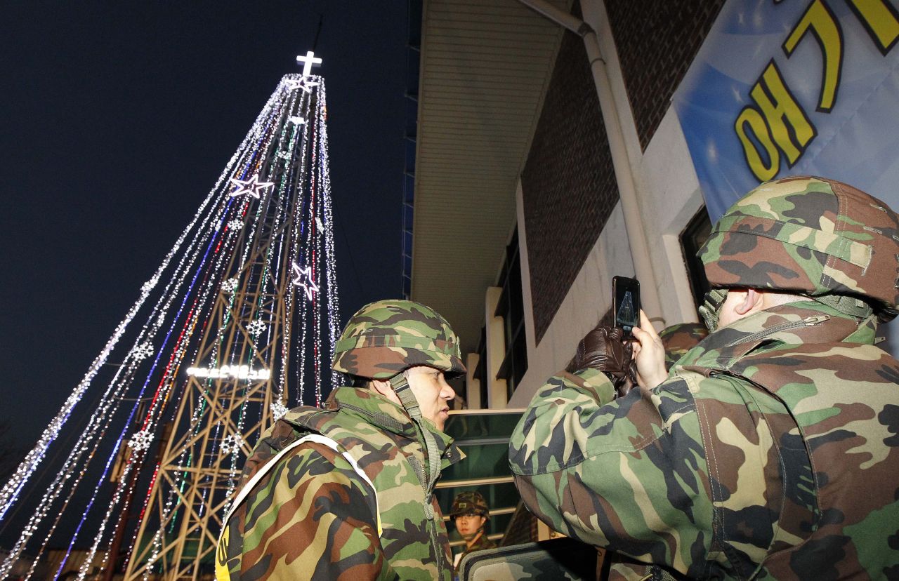 South Korean soldiers stand guard as Christians stage a lighting ceremony in front of a Christmas tree atop a military-controlled hill near the tense land border in Gimpo, west of Seoul, on December 21, 2010. North Korea has objected to Christmas trees at the border since the 1960s.
