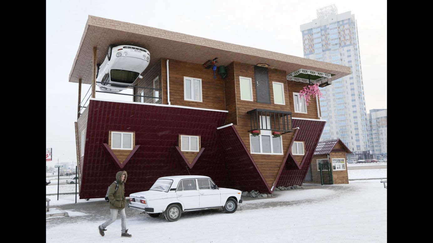 A man passes an upside-down house in Krasnoyarsk, Russia, on Sunday, December 14. The house was constructed as an attraction for local residents and tourists.