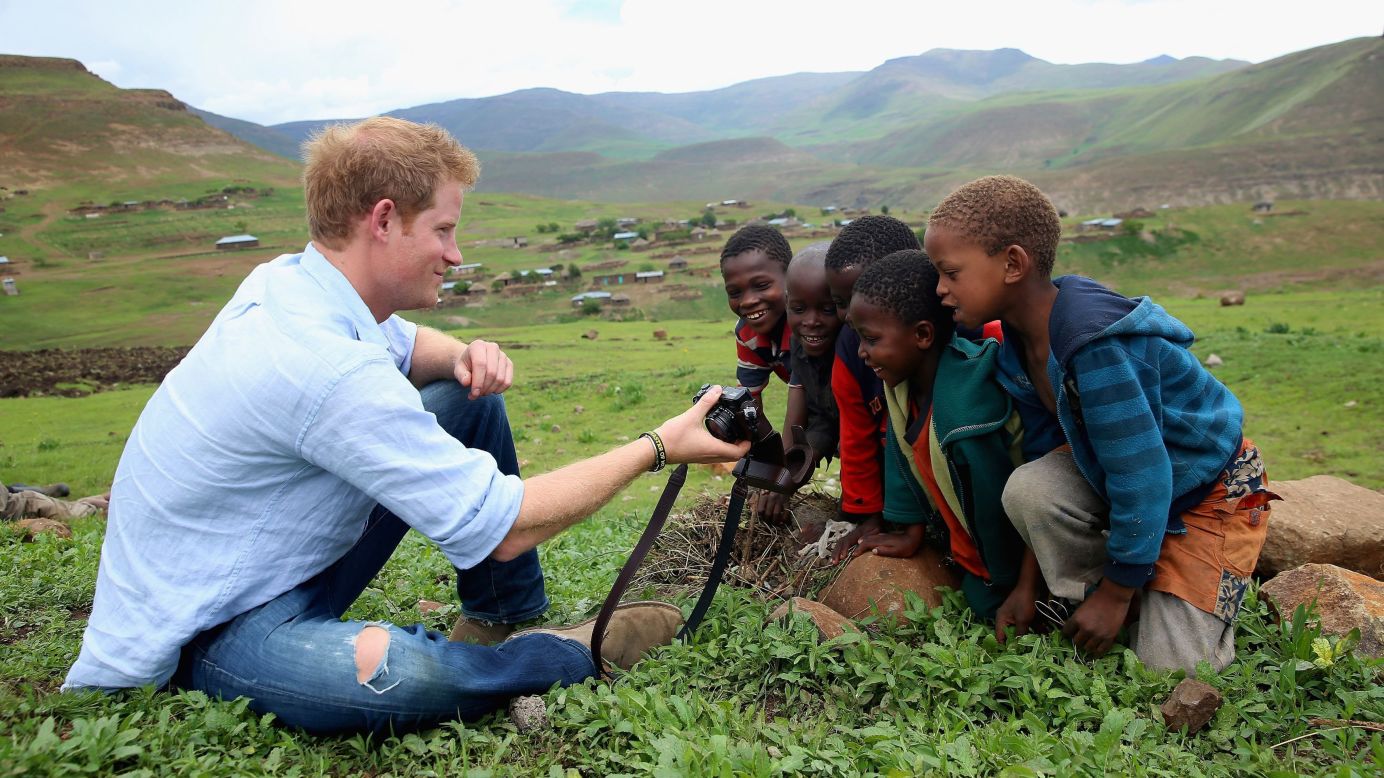Britain's Prince Harry shows children a photograph he took during a visit to Mokhotlong, Lesotho, on Thursday, December 18. The prince co-founded a charity, Sentebale, that built a school in the town.