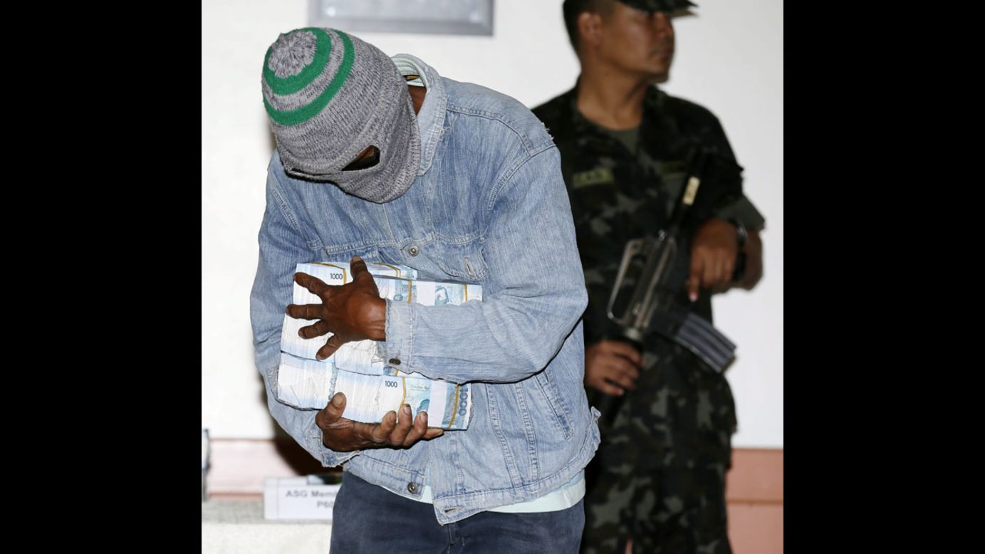 A civilian informant at Camp Aguinaldo, east of Manila, Philippines, holds a reward of 5.3 million Philippine pesos (nearly $120,000 U.S.) for the arrest of suspected Abu Sayyaf militants on Tuesday, December 16. The bounty was part of anti-terrorism efforts in the Philippines.
