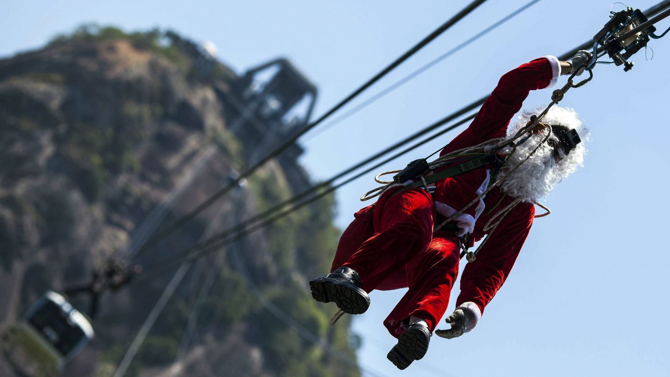 A man dressed as Santa Claus slides down a rope of the cable car transporting visitors up Rio de Janeiro's Sugarloaf Mountain on Thursday, December 18.