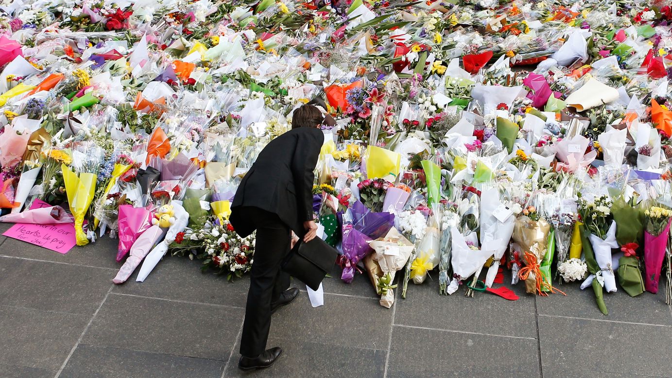 A man places flowers to pay his respects to the victims of <a href="http://www.cnn.com/2014/12/14/world/gallery/sydney-police-operation/index.html" target="_blank">the cafe siege in Sydney</a> on Tuesday, December 16.