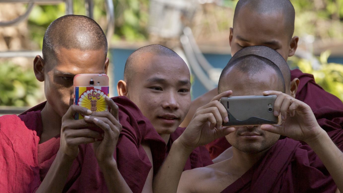 Buddhist monks take pictures at a courthouse in Yangon, Myanmar, as they wait to see Philip Blackwood after a court hearing on Thursday, December 18. Blackwood, general manager of the V Gastro Bar, and two business partners were arrested last week after an online advertisement for the bar showed a psychedelic image of Buddha wearing headphones.