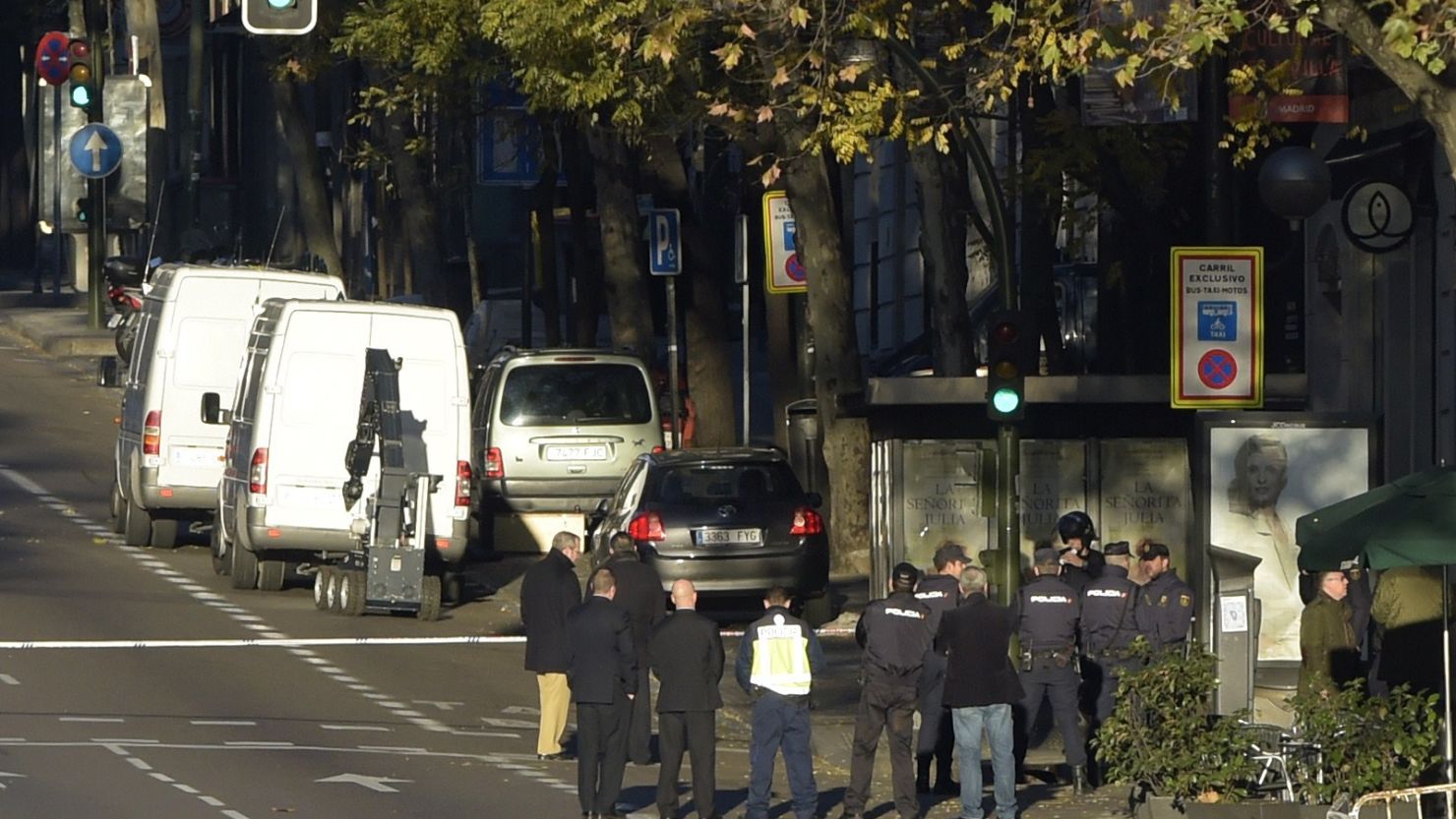 Spanish policemen and officials stand past the robot and vans of bomb disposal experts close to the Spanish Popular Party's headquarters after a man rammed his car with two gas cylinders into the political party's building, in Madrid.