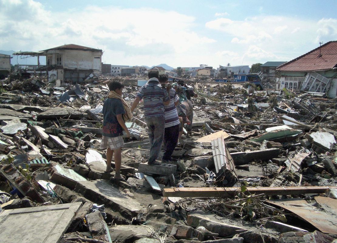 Family members carry away the body of a realative in Banda Aceh after a magnitude 9.0 earthquake and tsunami.