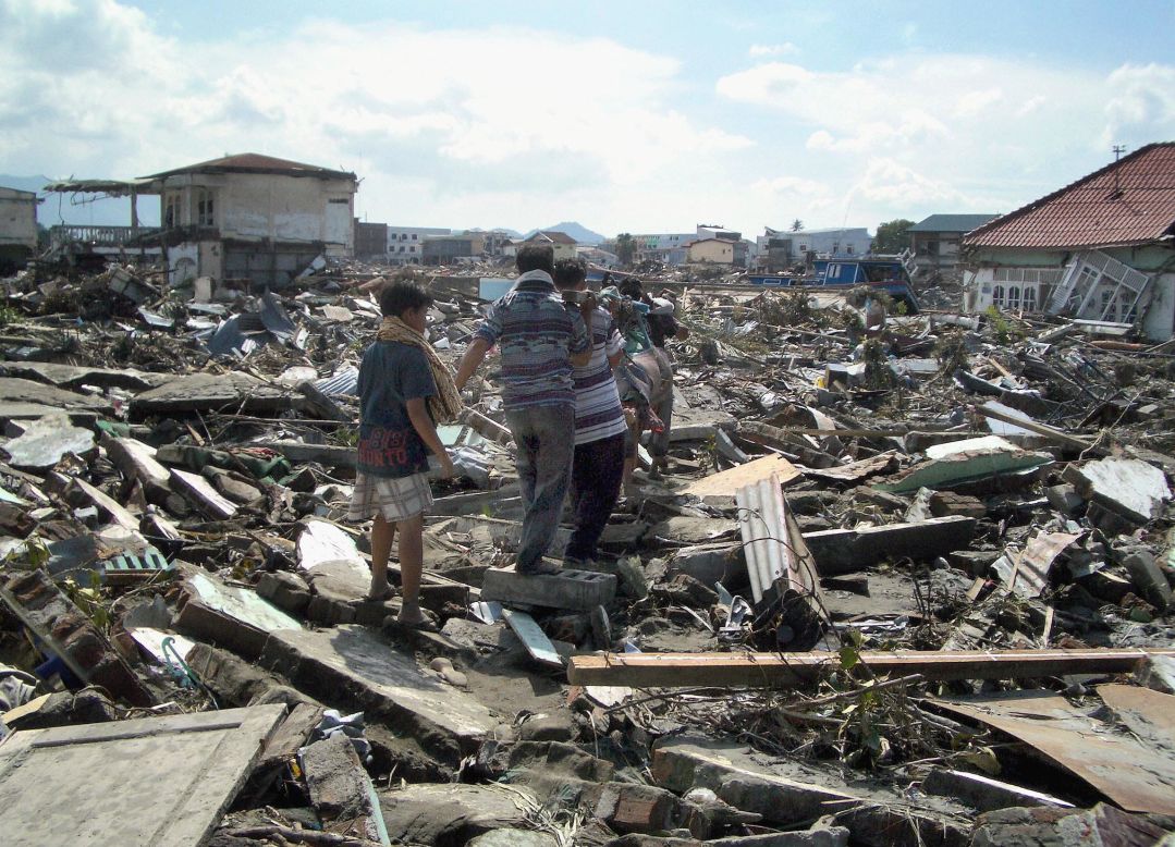 Local residents in Banda Aceh carry away the body of a dead relative the day after the disaster on December 27, 2004.