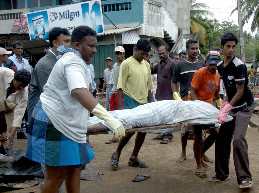 Sri Lankan health officials and relatives carry the body of a dead man away in Galle on December 27, 2004.