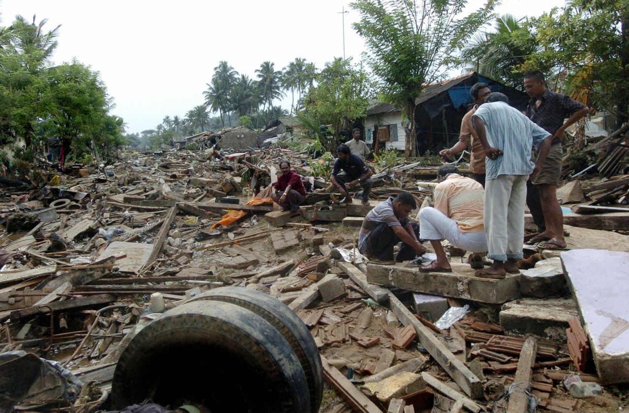 Sri Lankan men sort through debris of their destroyed homes in Galle on December 27, 2004. 