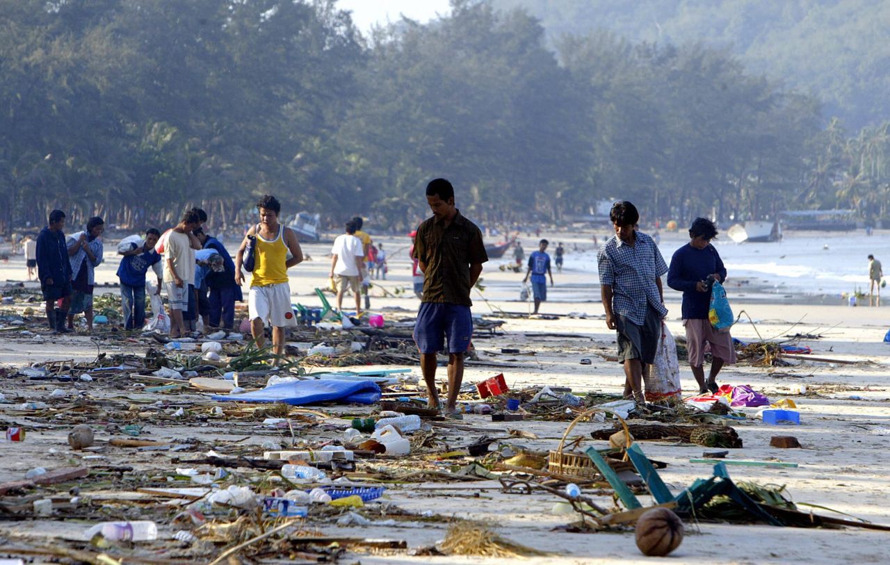 People walk through debris along the shoreline of Pathong beach of Phuket island, December 27, 2004, a day after the disaster. 