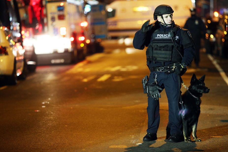 An officer with a police dog monitors the scene on the evening of December 20. 