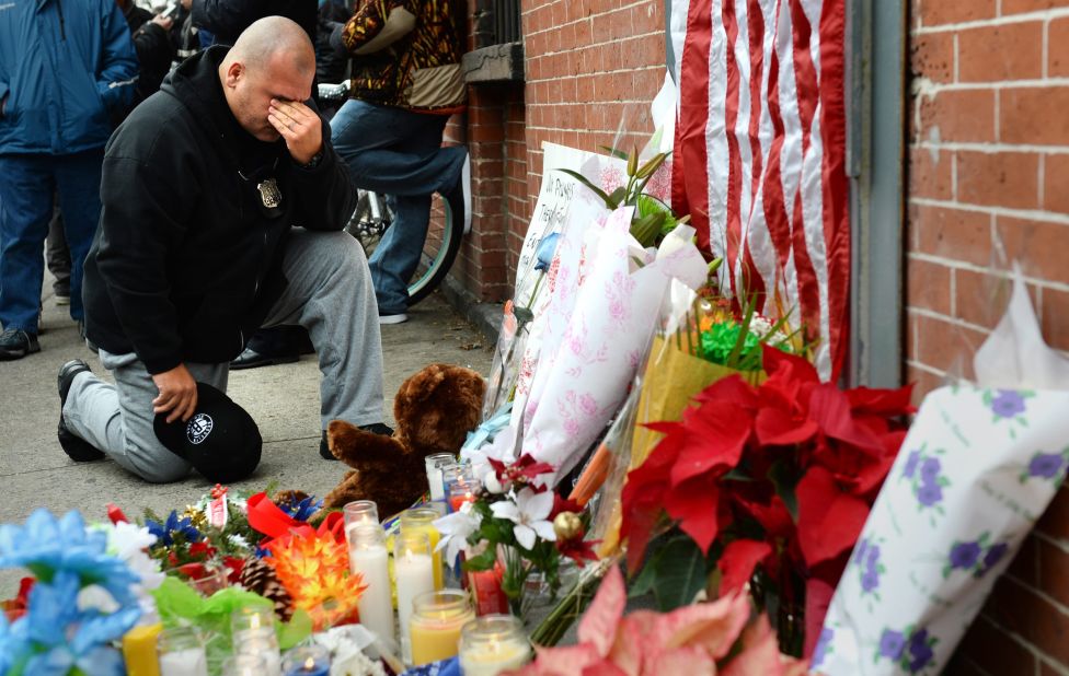 A New York City police officer kneels on Sunday, December 21, in front of a small memorial for two police officers who were killed  in Brooklyn, New York, on Saturday. 