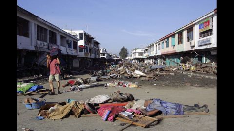 A man covers his mouth as he walks amid bodies and debris in Banda Aceh on December 28, 2004.