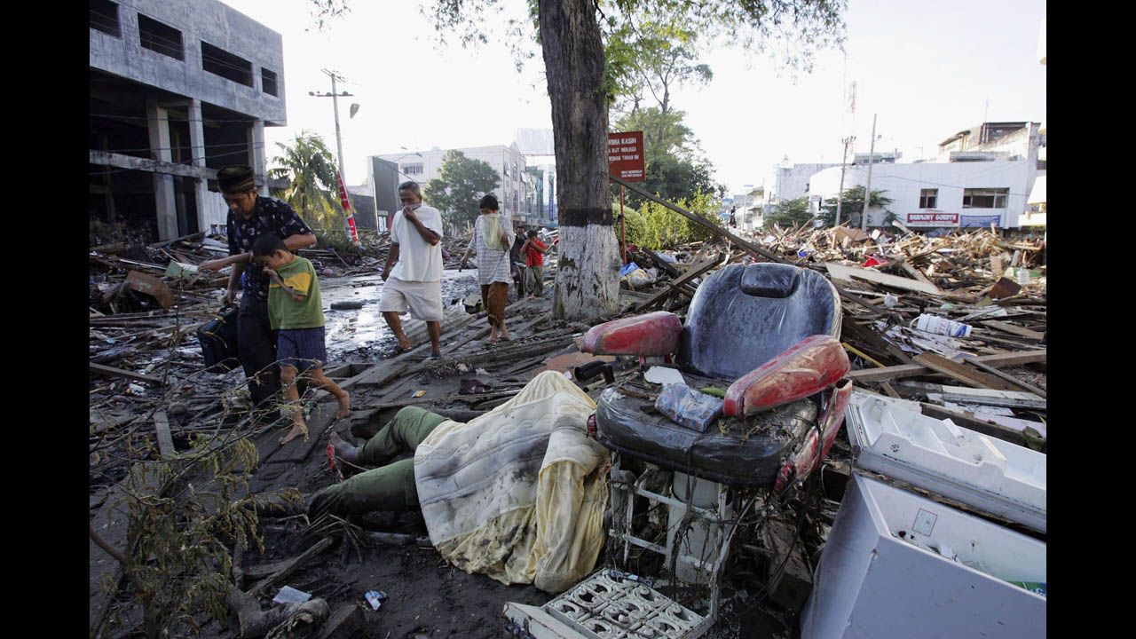 Locals in Banda Aceh walk with their faces covered as they pass bodies and debris on December 28, 2004.
