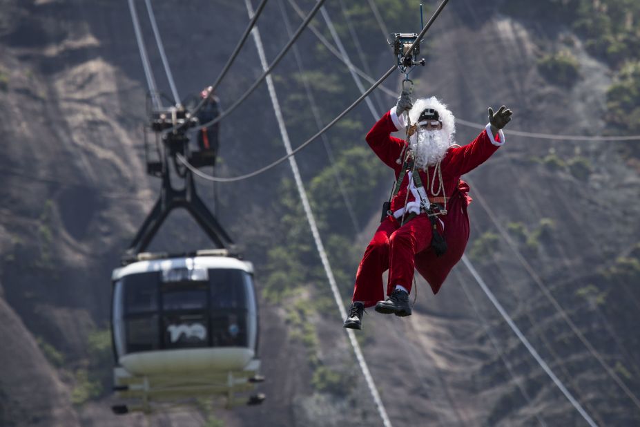 Santa takes a zip line away from Sugarloaf Mountain after riding on top of a cable car in Rio de Janeiro.