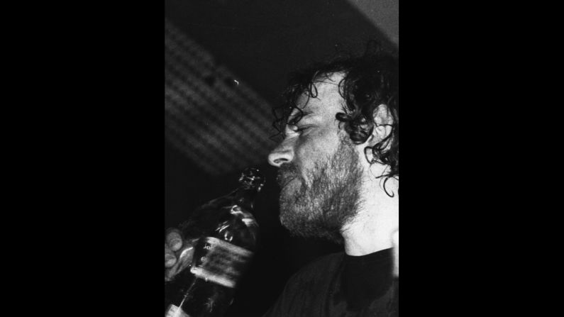 Cocker takes a swig of whiskey during a performance while on tour in Australia. His career nearly derailed over his use of drugs and alcohol in the 1970s.