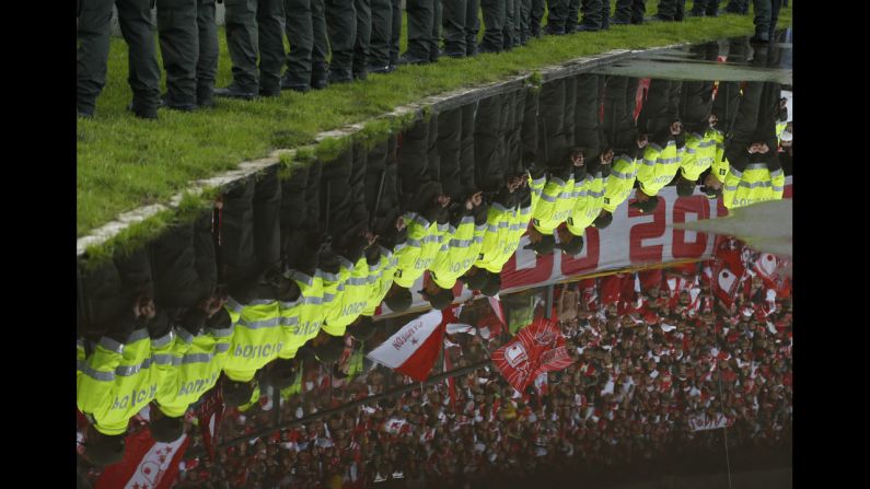 Fans and police officers are seen reflected in a puddle during the Colombian soccer league final game against Deportivo Independiente Medellin in Bogota, Colombia, on December 21.