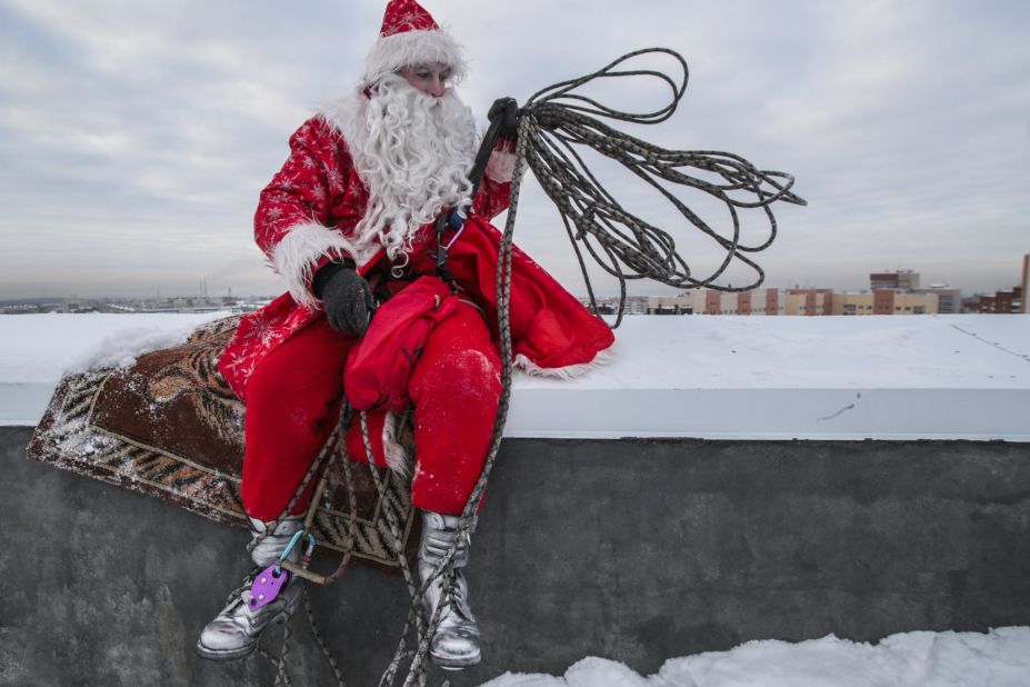 A performer dressed as Father Frost, the Russian equivalent of Santa, rests on a high-rise building in Kemerovo, Russia.