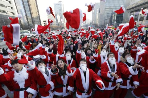 Volunteers in Santa outfits toss their hats into the air before delivering gifts to the poor in Seoul, South Korea.