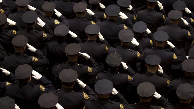 Officers salute during the New York Police Department promotion ceremony on Friday, December 19.