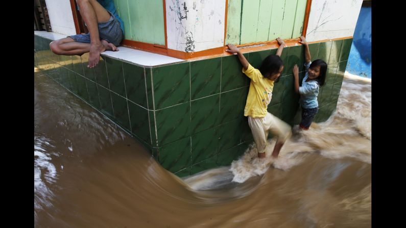 Children walk through a flooded street in Jakarta, Indonesia, on Tuesday, December 23. 