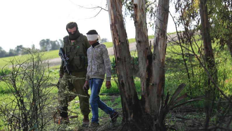 An Israeli soldier walks with a detained Palestinian teenager who the military said illegally crossed into Israel near the Gaza border, Wednesday, December 24.