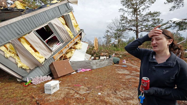 Chasity Magee reacts near her family's mobile home in Columbia, Mississippi, on Wednesday, December 24. The home was flipped on top of a neighbor's during a storm that killed four in the state.